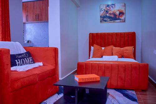 a bedroom with a red bed and a couch at Kakamega bransoncomfort in Kakamega