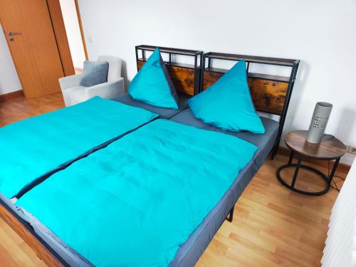 a bedroom with a bed with blue pillows and a chair at FeWo Dresden-Hellerau in Dresden