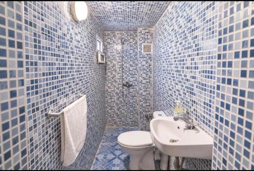 a blue tiled bathroom with a toilet and a sink at Riad Fes Layan in Fez