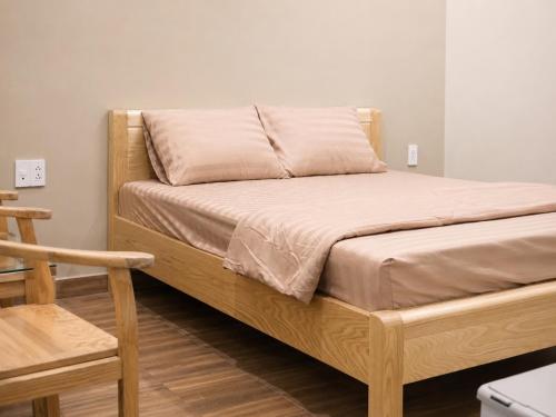 a bed with a wooden frame with a pillow on it at KAKA HOTEl - KDC TÂN ĐỨC in Ðức Hòa