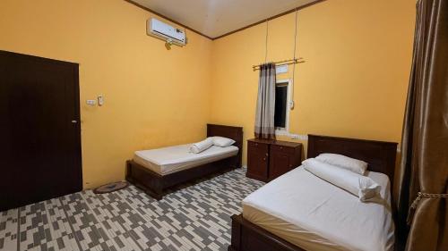 two beds in a room with yellow walls at Karang Besi Losmen in Biha