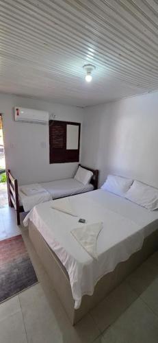 a bedroom with two beds in a room at Pousada Parque dos Coqueiros in Piaçabuçu