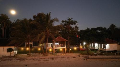 a house on the beach at night with the moon at Karang Besi Losmen in Biha