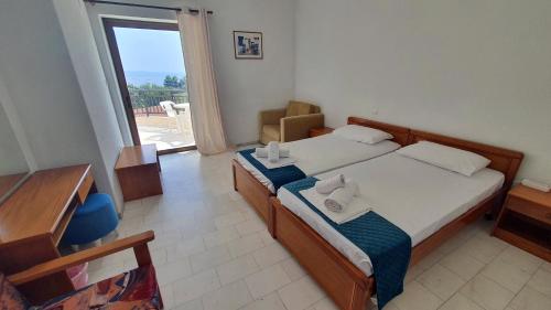 a bedroom with two beds and a large window at Hotel Pashos in Kriopigi