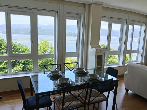 a dining room with a table and chairs and windows at Casa Vistas in Santa Marta de Ortigueira