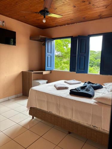 a bedroom with a large bed with blue windows at Pousada da Cida in Lençóis