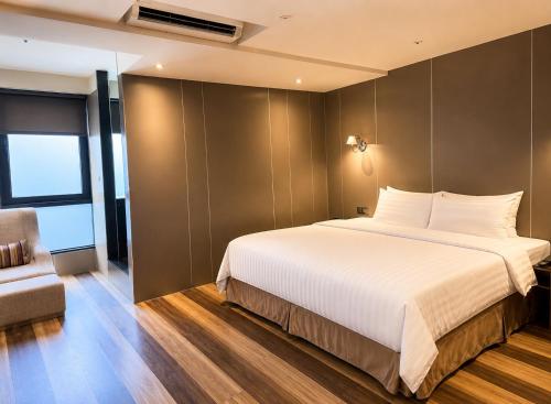 a bedroom with a large white bed and a chair at Hotel Relax I in Taipei