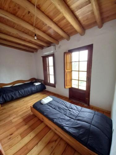 two beds in a room with wooden floors and windows at Casa Petricor in Río Tercero