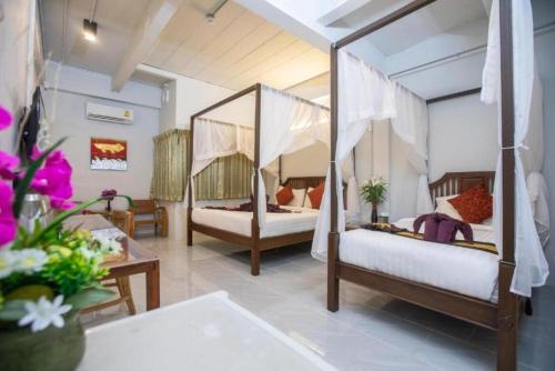 a bedroom with two beds and a table with flowers at Sabaidee Chiangmai Hotel in Chiang Mai