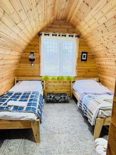 two beds in a wooden room with a window at Aalam ordo in Shabdan