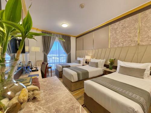 a hotel room with two beds and a plant at ODST AL Madinah Hotel - فندق اودست المدينة in Medina