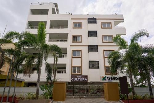 a white building with palm trees in front of it at Treebo Cultura in Hyderabad
