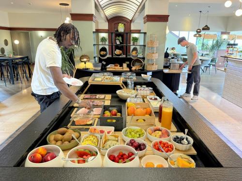 two men preparing food at a buffet in a restaurant at Hôtel L'Amandier in Libramont
