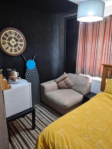 a bedroom with a bed and a couch and a clock at Levens Terrace, Barrow Spa Therapy in Barrow in Furness