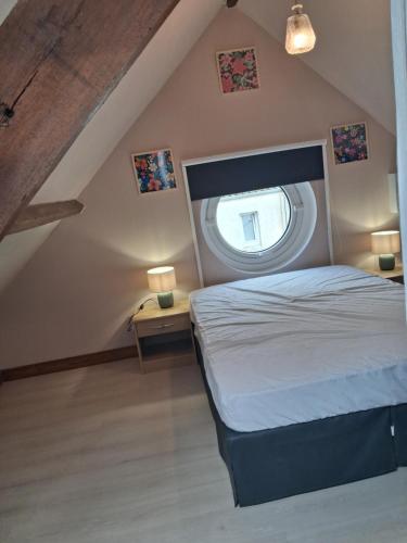 a bedroom with a bed with a round window at Chez Cosette, studio in Montreuil-sur-Mer