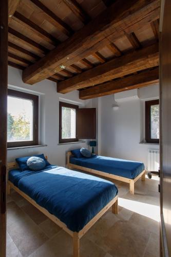 two beds in a room with wooden ceilings at Peaceful Umbria views & heated infinity pool in Umbertide