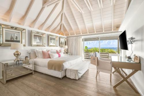 ein Schlafzimmer mit Bett, Schreibtisch und Fenster in der Unterkunft Le Toiny Hotel & Beach Club in Toiny