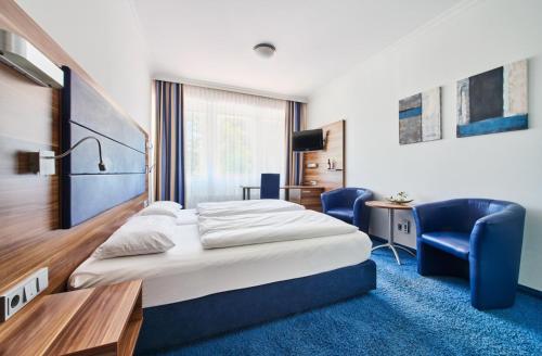 a hotel room with a bed and a desk and chairs at Hotel am Gröbenbach in Gröbenzell