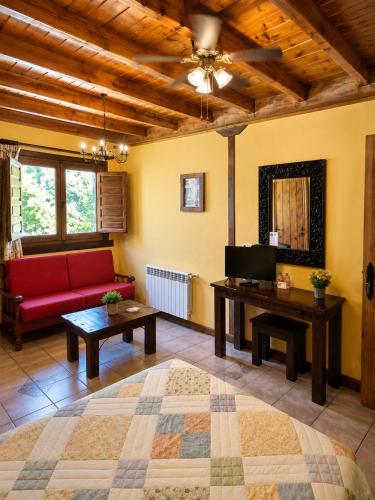 a living room with a red couch and a table at Posada La Vieja Escuela Valles Pasiegos in San Roque de Ríomiera