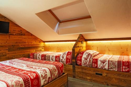 a row of four beds in a room with wooden walls at Bertuzzi Homes in Aprica