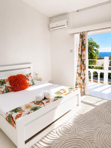 a white bedroom with a bed and a balcony at Cocoon Signature in Flic-en-Flac