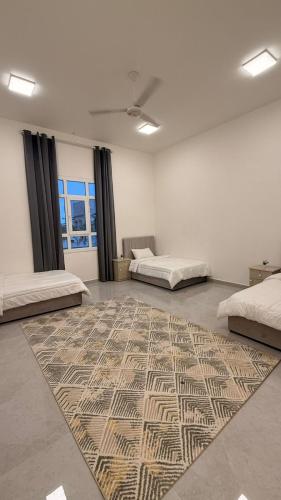 a room with two beds and a rug on the floor at منزل لافيدا La Vida Home in Salalah