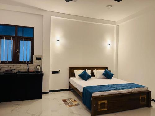 a bedroom with a bed with blue pillows and a sink at Villa Calista Weligama in Weligama