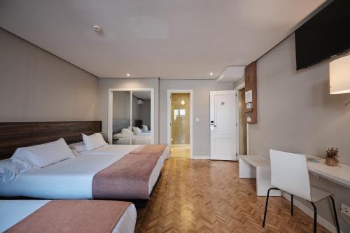 a hotel room with two beds and a desk at Hotel Mogay in Chantada