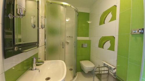 a green bathroom with a sink and a shower at U Mateusza 607-737-859 Widok na Jezioro Solińskie in Polańczyk