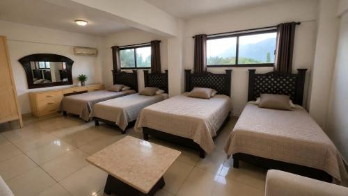 a room with three beds and a mirror at Hotel Siesta Escamela in Ixtaczoquitlán