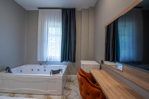 a white bathroom with a tub and a window at Demirkapı Otel in Uzungöl