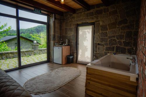 a bathroom with a tub and a stone wall at Gafulluk Tatil Köyü in Araklı