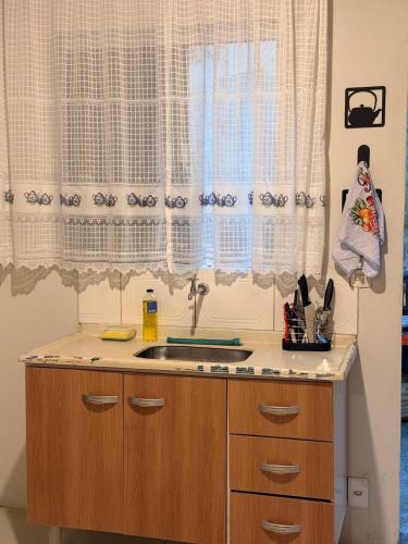 a kitchen with a sink and a window with curtains at Studio completo em Diamantina-MG in Diamantina