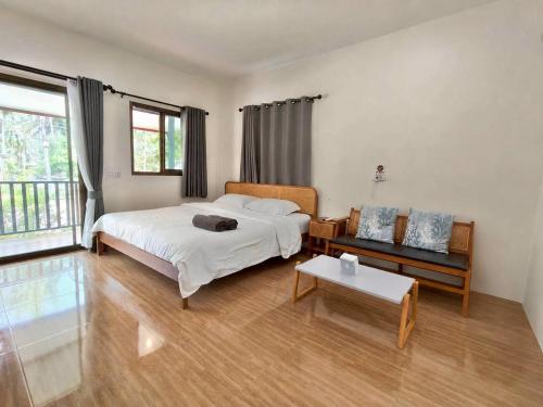 a bedroom with a bed and a couch and a table at First light beach bungalow in Ko Phangan