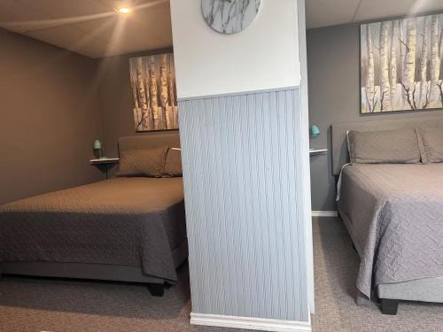 a room with two beds and a clock on the wall at La Spacieuse Riverstone CITQ3O1849 in Saint Pierre de Broughton