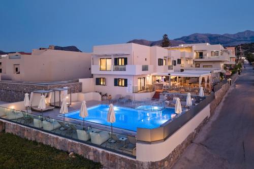 a villa with a swimming pool in front of a house at Mila Sissi Bay Hotel in Sisi