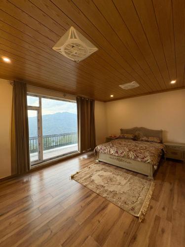 a bedroom with a bed and a large window at The Elysian Villa in Murree