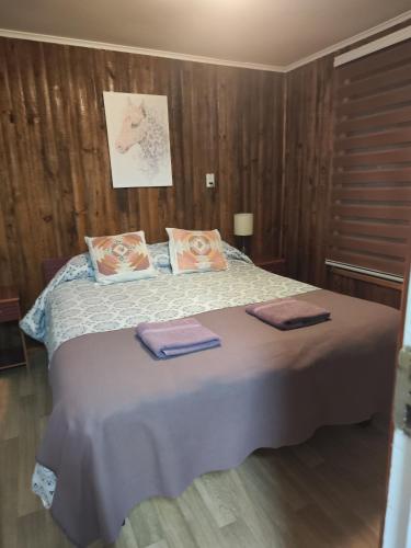 a bedroom with a bed with two towels on it at Cabañas Campestres Las Rosas in Punta Arenas