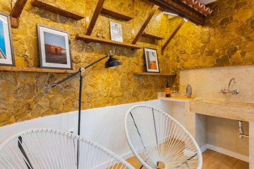 two white chairs in a room with a stone wall at Casa Limão in Charneca