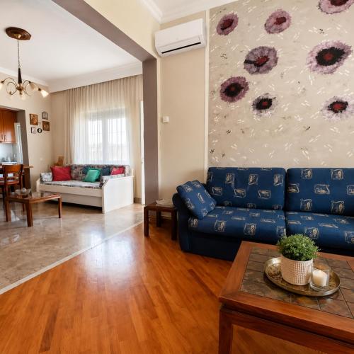 a living room with a blue couch and a painting at Kolhida home in Kilkis