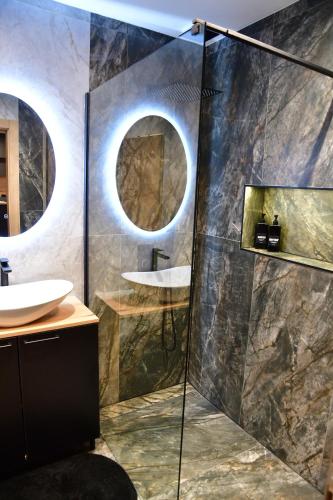 a bathroom with two sinks and a shower with two mirrors at Politon Suites in Zaječar