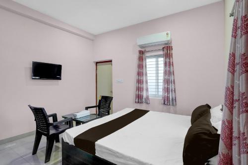 a bedroom with a bed and a desk and a television at Hotel O Candel Light Inn in Bhubaneshwar