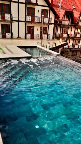 a pool of blue water in front of a building at Villa Nikoletta SPA in Bukovel