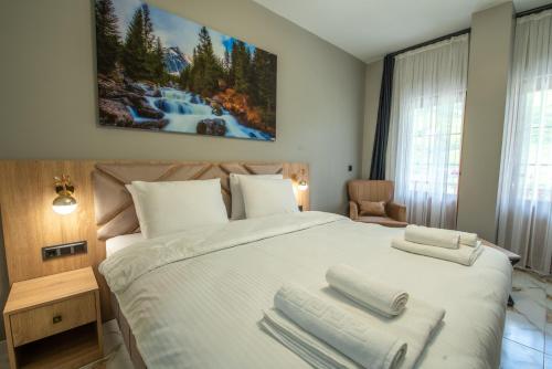 a bedroom with a large white bed with towels on it at Demirkapı Otel in Uzungöl