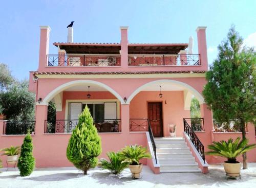 a pink house with a balcony on top of it at Villa Valia Seaside in Ipsos