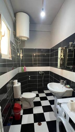 a bathroom with a black and white checkered floor at Garden Vila Apartment in Kamëz