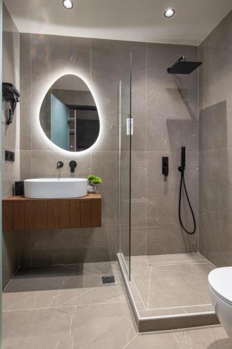 a bathroom with a sink and a shower with a mirror at Pnoe Boutique suites in Nikiti
