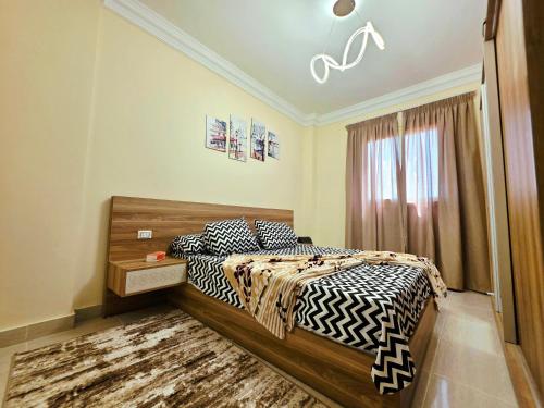 a bedroom with a bed with black and white sheets at Rahaf palm beach chalet in Ain Sokhna