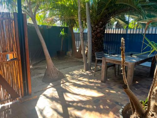 a patio with a wooden bench and palm trees at Blue Moon Guest Rooms in Bellville