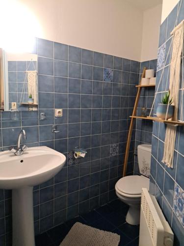 a blue tiled bathroom with a sink and a toilet at L'Auberge in Saint-Martin-dʼArmagnac